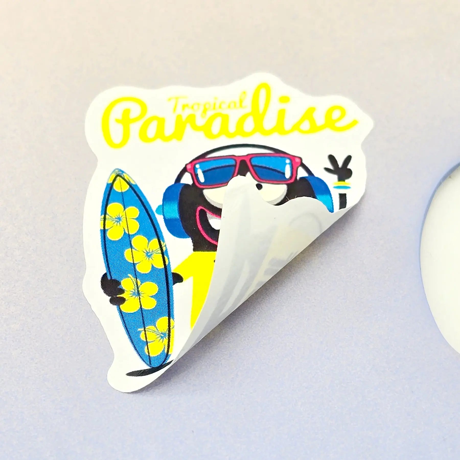 Custom die-cut PVC sticker being peeled from backing paper, showing clean cut edges and strong adhesive